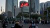FILE - Residents pass near a commercial district with a screen showing the Chinese national flag in Beijing, Nov. 18, 2023. China's economic weakness appears to have made international investors wary. 