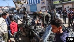 FILE - People check a car in which two journalists, Mustafa Thuria, a video stringer for news service Agence France-Presse, and Hamza Wael Dahdouh, a journalist with Al Jazeera television network, were killed in the Gaza Strip on Jan. 7, 2024. 