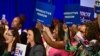 Sejumlah perempuan memegang spanduk sambil mendengarkan Wakil Presiden Kamala Harris berbicara tentang kebebasan reproduksi di El Rio Neighborhood Center, Tucson, Arizona, pada 12 April 2024. (Foto: AFP)