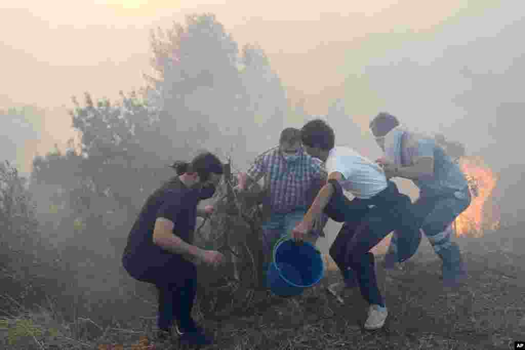 Local residents try to slow down flames approaching their houses in Alcabideche, outside Lisbon, Portugal, July 25, 2023.