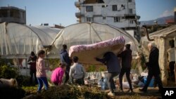 Local residents bring a mattress to a greenhouse where they shelter after the earthquake in Samandag, southern Turkey, Feb. 16, 2023