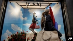 FILE - A woman walks past the Gucci store window at the Via Montenapoleone fashion district, during the Milan's fashion week Sept. 25, 2020.
