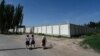 FILE - Children pass an old detention center near Kashgar, China, July 15, 2023. Since 2017, more than a million Uyghurs and other Muslims have been swept into internment camps. Beijing says inhabitants "graduated' and left after learning job skills.