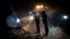 Members of NGOs Deathcare Embalming Team, left, and Turkish Kurt-Ar inspect the bucket of an excavator as they search for bodies of people who died during the earthquake in Kahramanmaras, Turkey, Feb. 17, 2023.