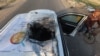 A Palestinian man rides a bicycle past a damaged vehicle where employees from the World Central Kitchen were killed in an Israeli airstrike, according to the NGO, in Deir al-Balah, Gaza Strip, April 2, 2024. 