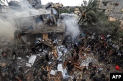 Warga Palestina berkumpul di sekitar rumah keluarga Shehada yang hancur menyusul pemboman Israel terhadap Rafah di Jalur Gaza selatan pada 14 Desember 2023. (Foto: AFP)