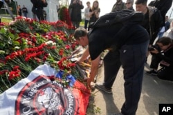 FILE - Seorang pejuang pasukan militer swasta Grup Wagner meletakkan palu godam, salah satu simbol Wagner, di sebuah tugu peringatan informal di sebelah bekas Pusat PMC Wagner di St. Petersburg, Rusia, pada 24 Agustus 2023.