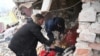 Dua orang mencari di antara puing-puing sebuah rumah setelah serangan rudal Rusia di desa Velyka Vilshanytsia, Ukraina, sekitar 50 km dari kota Lviv, hari 9 Maret 2023.
