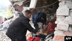 Dua orang mencari di antara puing-puing sebuah rumah setelah serangan rudal Rusia di desa Velyka Vilshanytsia, Ukraina, sekitar 50 km dari kota Lviv, hari 9 Maret 2023.