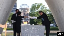 在广岛和平纪念公园举行的仪式上，广岛市长松井一实和死者家属代表将原子弹爆炸遇难者名单安放在纪念碑上。(2023年8月6日)