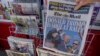 A woman buys a copy of the British Mail on Sunday newspaper at a news stand in London, July 14, 2024, showing the reaction to events at former U.S. President Donald Trump's campaign rally in Butler, Pennsylvania. 