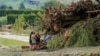 FILE - People stand next to debris in a flood-affected area in the aftermath of Cyclone Gabrielle near Napier, New Zealand, Feb. 16, 2023.