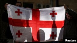დემონსტრანტებს უჭირავთ საქართველოს ეროვნული დროშა, "რუსული კანონის" საწინააღმდეგო აქციაზე