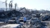 A man walks through wildfire wreckage Aug. 11, 2023, in Lahaina, Hawaii. 