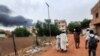 Smoke rises above buildings as people flee with some belongings, in Khartoum, Sudan, June 10, 2023. 
