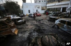 Palestinians check the site of the explosion at Ahli Arab Hospital, in Gaza City, Oct. 18, 2023.