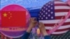 Seorang pedagang memajang dekorasi bunga di antara lingkaran yang diselimuti bendera China dan Amerika di Beijing pada 13 Mei 2023. (Foto: AP/Andy Wong)