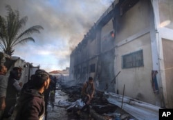 Warga Palestina mencoba memadamkan api di gedung pusat pelatihan kejuruan UNRWA yang digunakan para pengungsi sebagai tempat berlindung, setelah menjadi sasaran tank Israel di Khan Younis, Jalur Gaza selatan, 24 Januari 2024. (Foto: AP)