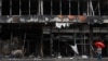 A woman carries an umbrella as she walks past a destroyed shopping mall in Bucha, in Ukraine's Kyiv region, Aug. 16, 2022. 