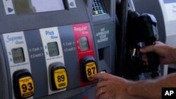FILE - A customer pumps gas at an Exxon gas station, May 10, 2022, in Miami.