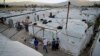 Syrian refugees walk by their tents at a refugee camp in the town of Bar Elias, in the Bekaa Valley, Lebanon, July 7, 2022.