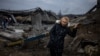 A woman rests after crossing a destroyed bridge as she evacuates from the city of Irpin, northwest of Kyiv, on March 7, 2022.