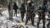 FILE - Members of the Senegalese Armed Forces walk past discarded rockets at a recently captured Movement of Democratic Forces of Casamance (MFDC) rebel base in Blaze Forest, Feb. 9, 2021. 