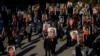 FILE - In this photo taken Jan. 8, 2021, people hold signs with images of the victims of the downed Ukraine International Airlines Flight PS752.