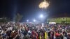 Fireworks light up the sky as people react while they celebrate after counting down to the new year at Miracle Center Cathedral in Kampala, Uganda, Jan. 1, 2023. 