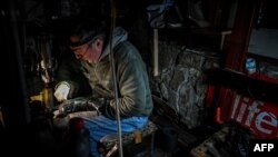 A cobbler works under the flashlight during a blackout in Lviv on Dec. 16, 2022, after Russian strikes targeted the power infrastructure. 
