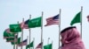 FILE - A man stands under U.S. and Saudi Arabian flags prior to a visit by President Joe Biden, at a square in Jeddah, Saudi Arabia, July 14, 2022. 