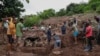 Sejumlah kerabat membantu personel SAR dari Kepolisian Afrika Seltatan (SAPS) membersihkan puing-puing dalam operasi pencaraian sepuluh orang yang hilang saat banjir di wilayah KwaNdengezi, di luar Kota Durban, Afrika selatan, 15 April 2022. (Foto: Phill Magakoe / AFP)