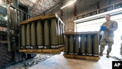 Staf Angkatan Udara AS Sersan. Cody Brown, kanan, dengan Skuadron Pelabuhan Udara ke-436, memeriksa palet peluru 155 mm yang akan dikirim ke Ukraina, 29 April 2022, di Pangkalan Angkatan Udara Dover, AS. (Foto: AP)