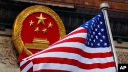 FILE - Bendera Amerika dikibarkan di samping lambang nasional China di Balai Besar Rakyat China di Beijing, 9 November 2017.