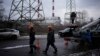 FILE - Utility workers walk next to a power plant after a missile attack in Kyiv, Ukraine, Jan. 26, 2023.