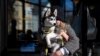 Madeleine Russell, buries her face into the fur of her 4-month-old husky, Stevie Nicks, to stay warm while waiting for a friend outside a coffee shop in Providence, RI, Feb. 3, 2023. 
