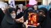 FILE - A protester shows a cartoon of French President Emmanuel Macron during a protest condemning the French magazine Charlie Hebdo for republishing cartoons insulting Iran's Supreme Leader Ayatollah Ali Khamenei, in Tehran, Iran, Jan. 11, 2023.