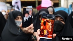 FILE - A protester shows a cartoon of French President Emmanuel Macron during a protest condemning the French magazine Charlie Hebdo for republishing cartoons insulting Iran's Supreme Leader Ayatollah Ali Khamenei, in Tehran, Iran, Jan. 11, 2023.