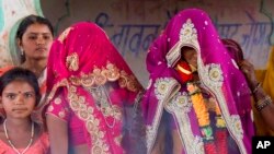 FILE - In this April 17, 2017, photo, an underaged bride, right, stands with family members during her marriage at a Hindu temple near Rajgarh, Madhya Pradesh state, India.