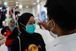 Seorang tenaga kesehatan memeriksa suhu penumpang MRT di sebuah stasiun, Jakarta.