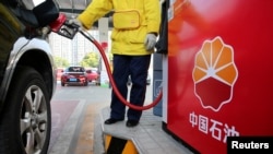 Seorang pegawai di sebuah pom bensin di Nantong, Jiangsu, China, tampak mengisi mobil pelangggan pada 28 Maret 2018. (Foto: Reuters/Stringer)