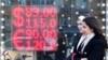 Orang-orang berjalan melewati layar yang menunjukkan nilai tukar mata uang dolar Amerika dan Euro terhadap rubel Rusia di Moskow, pada 28 Februari 2022. (Foto: Ap/Pavel Golovkin)