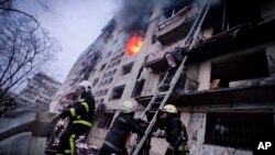 In this photo released by Ukrainian State Emergency Service press service, firefighters work at an apartment building hit by shelling in Kyiv, Ukraine, Monday, March 14, 2022. (Ukrainian State Emergency Service via AP)