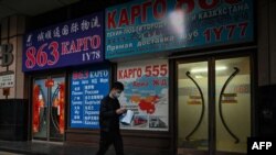 FILE - A man walks past a store advertising cargo shipping to Russia and other countries, along a street in Beijing, March 4, 2022. 