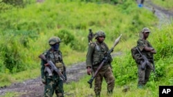 FILE - M23 rebels stand with their weapons in the town of Kibumba, in the eastern of Democratic Republic of Congo, Dec. 23, 2022.