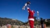 Brian Martinez mengenakan kostum Sinterklas, bermain dengan putranya, Braxon (4), di Lake Hollywood Park, Los Angeles, Sabtu, 24 Desember 2022. (AP/Damian Dovarganes)