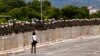 A woman walks in front of military police prepared for an announced protest by supporters of former President Jair Bolsonaro, in Brasilia, Brazil, Jan. 11, 2023. The protests did not take place.