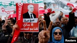 FILE - People carry banners and flags during a rally in support of Tunisian President Kais Saied in Tunis, Tunisia, May 8, 2022.