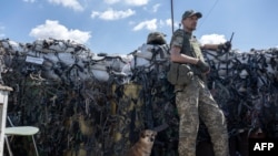 A Ukrainian soldier, accompanied by a dog, keeps position on the front line in Mykolaiv region on July 23, 2022, amid the Russian invasion of Ukraine.