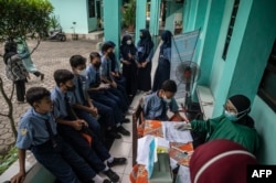 Seorang nakes melakukan tes antigen COVID-19 pada siswa SMP di Surabaya, 9 Juni 2022. (Foto: JUNI KRISWANTO/AFP)